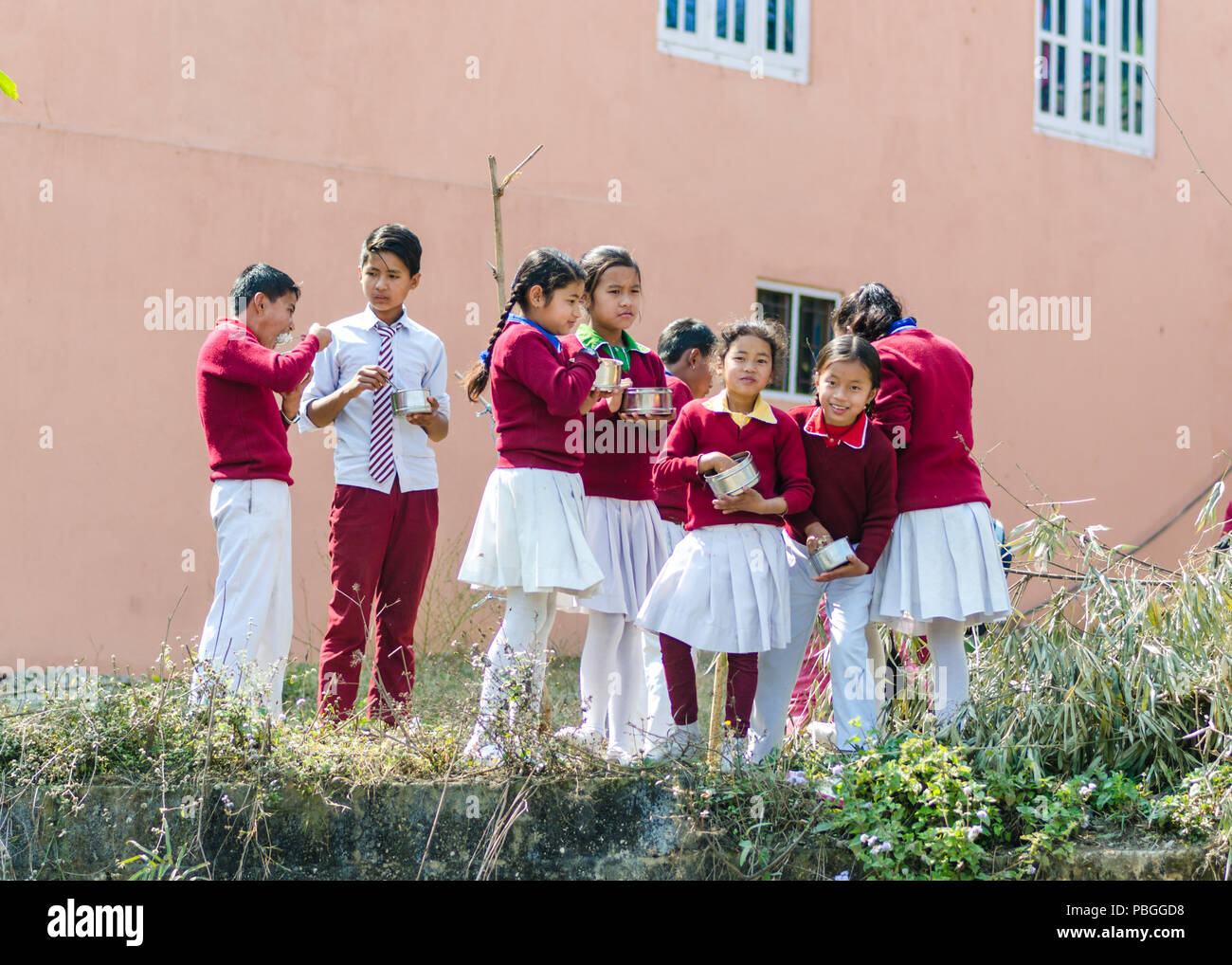 Scolari in uniforme durante la pausa pranzo nelle zone rurali del Nepal Foto Stock