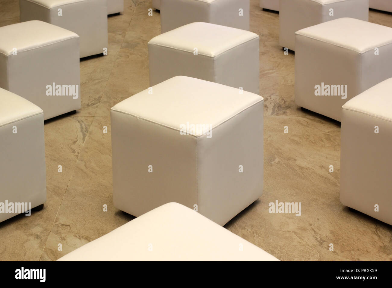 Pila di bianco sedia in pelle con pavimento di marmo Foto Stock