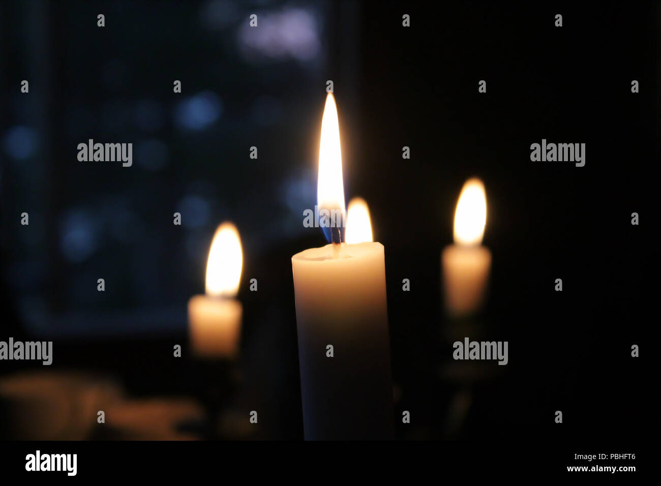 Quattro candele accese nel buio Foto Stock