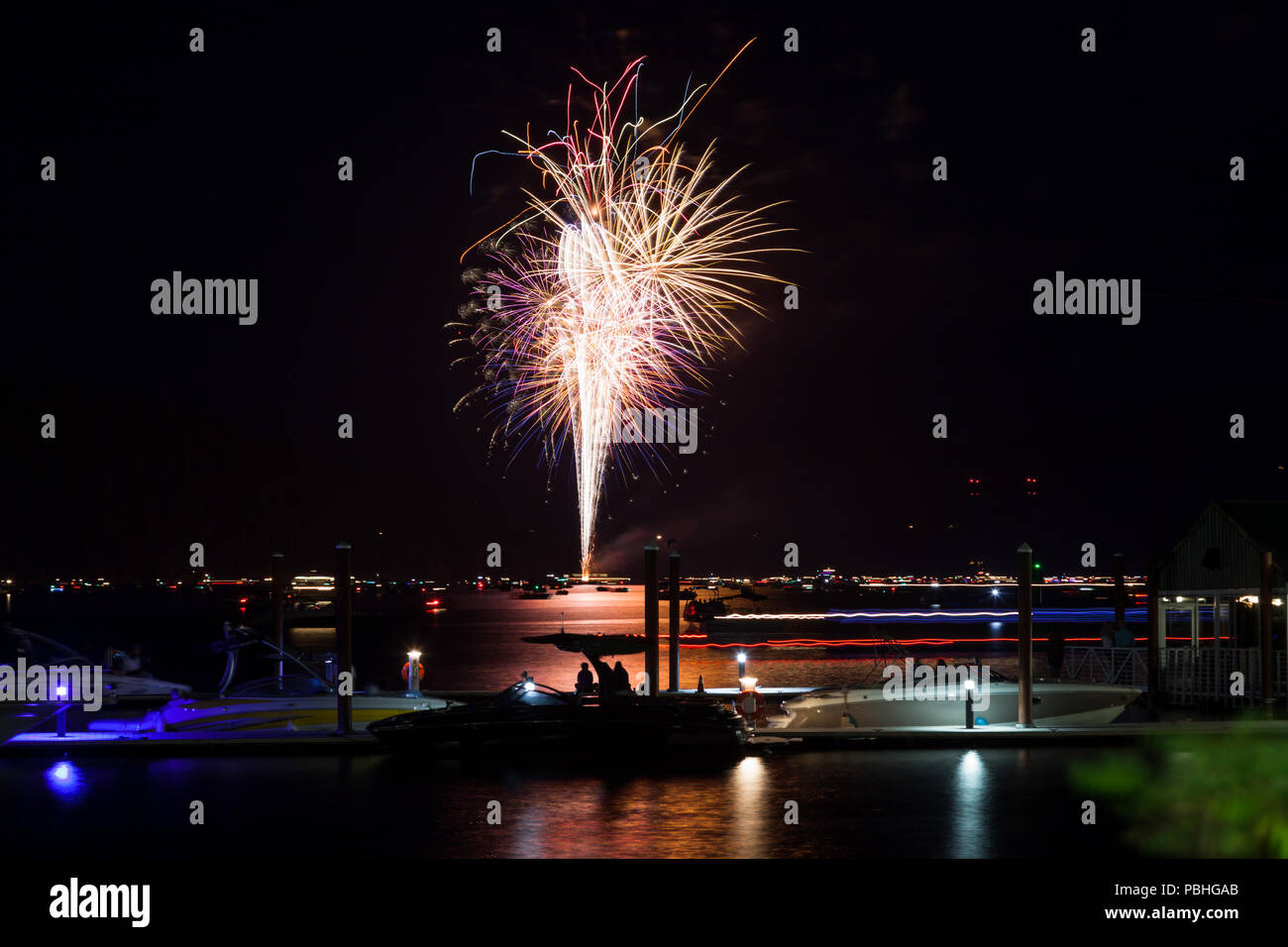 Bellissimo il quarto di luglio Fireworks incandescente sopra il lago di Coeur d'Alene in Idaho con diverse imbarcazioni affollare l acqua e il dock. Foto Stock