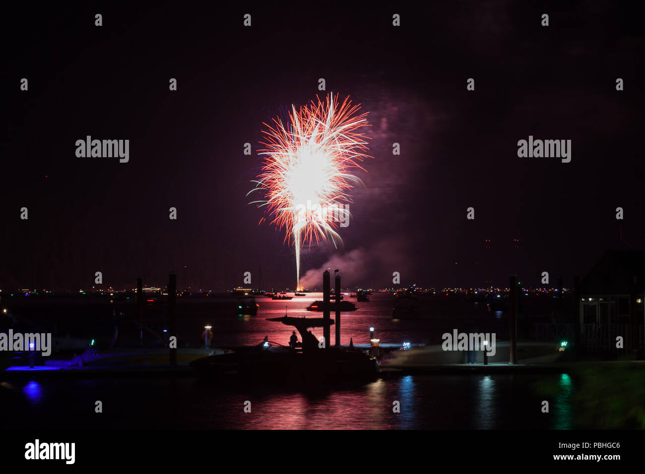 Bellissimo il quarto di luglio Fireworks incandescente sopra il lago di Coeur d'Alene in Idaho con diverse imbarcazioni affollare l acqua e il dock. Foto Stock