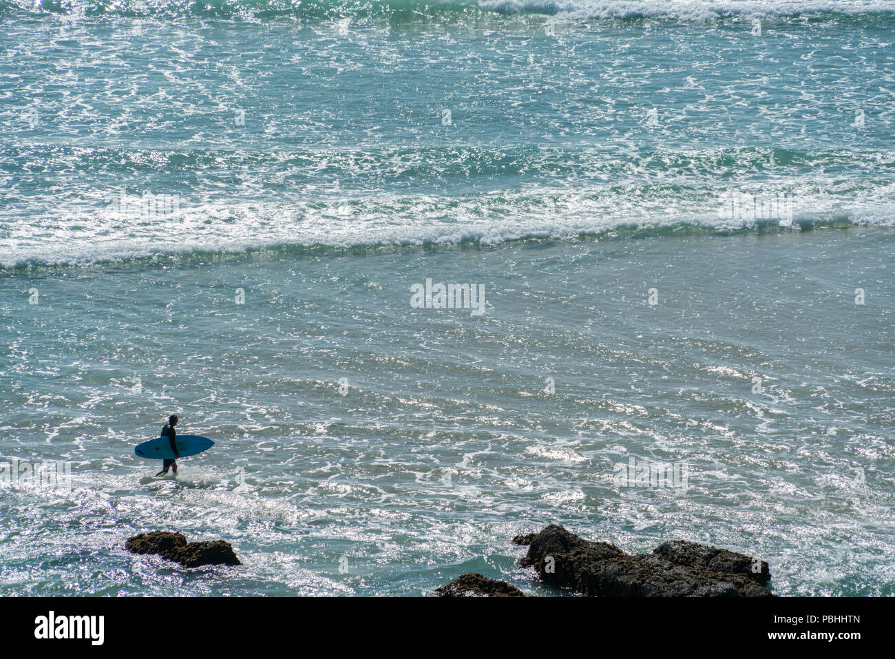 Background ampia spiaggia per il surf con surfer walikng scheda di trasporto attraverso i fondali. Foto Stock