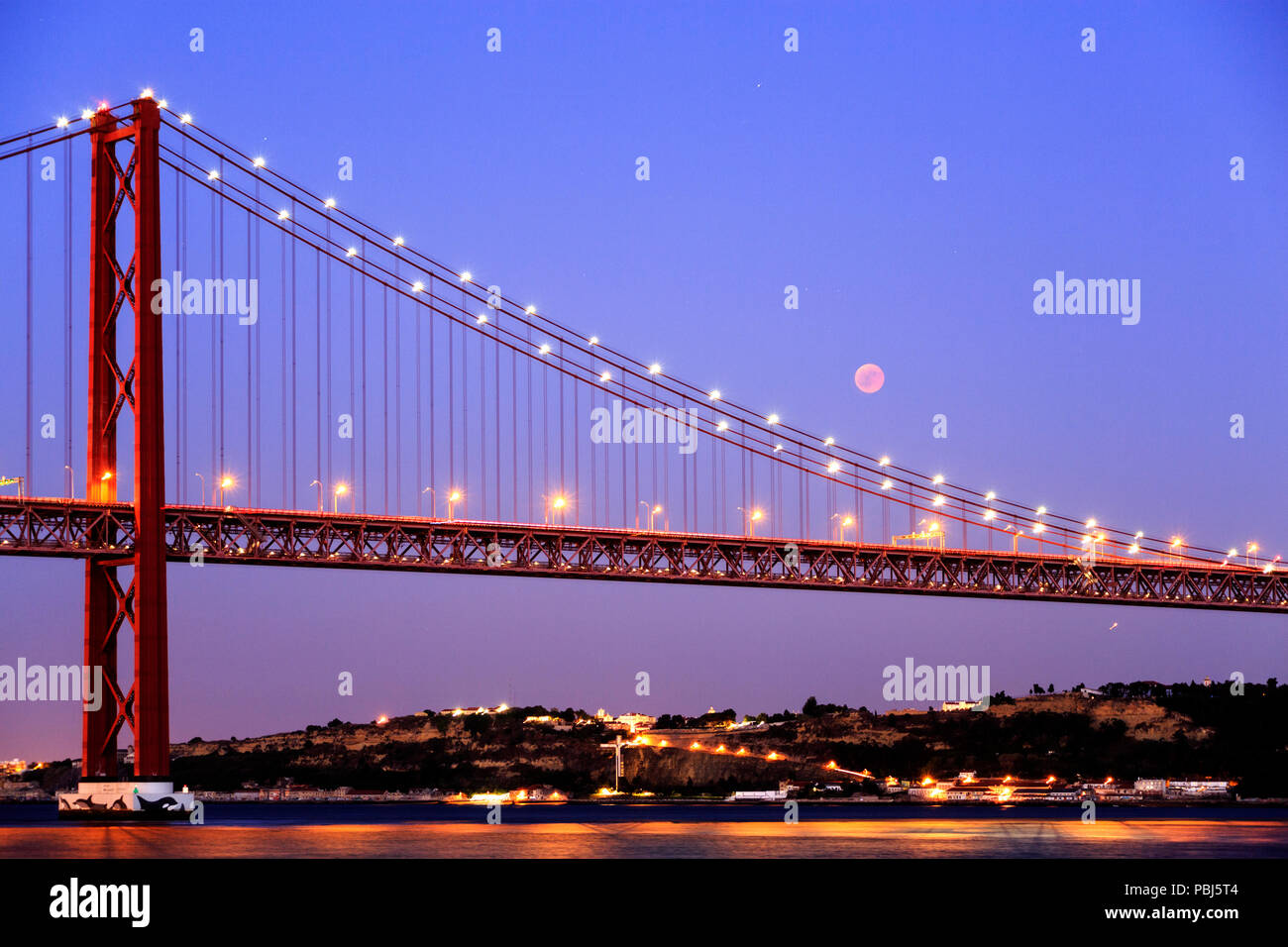 Vista dell'eclisse lunare, la più lunga luna di sangue del XXI secolo, oltre il Ponte 25 Aprile a Lisbona, Portogallo Foto Stock