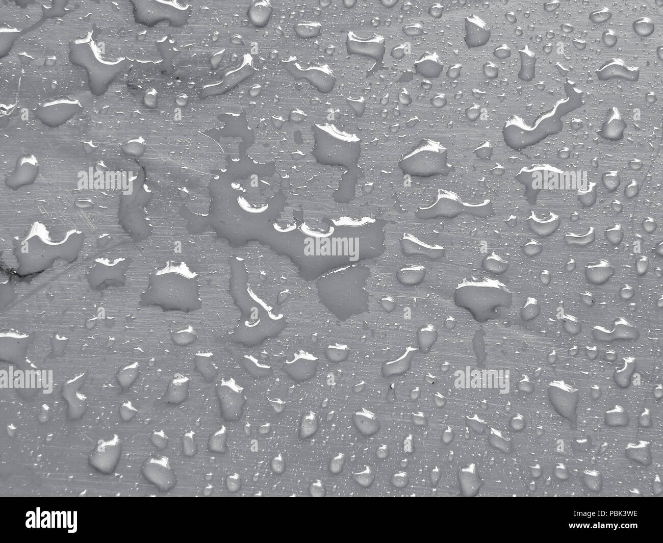 Gocce d'acqua sulla tranquilla di colore grigio della superficie metallica Foto Stock