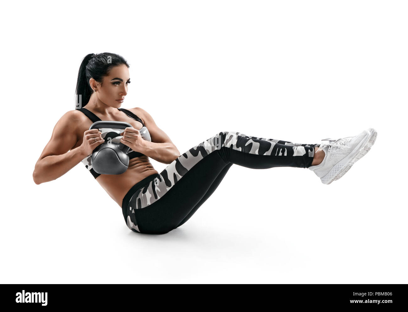 Donna muscolare facendo sedere fino esercizio con kettlebell, abs. Foto di attraente donna latina in silhouette su sfondo bianco. Forza e motivazioni Foto Stock