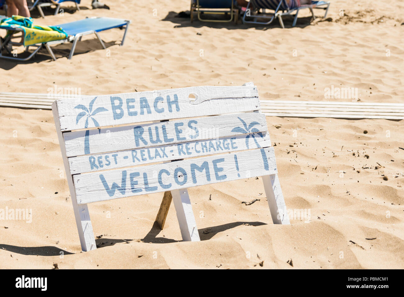 White cartello in legno sulla spiaggia, con segno: Spiaggia regole - il riposo, il relax, ricaricare e benvenuti alla spiaggia Foto Stock