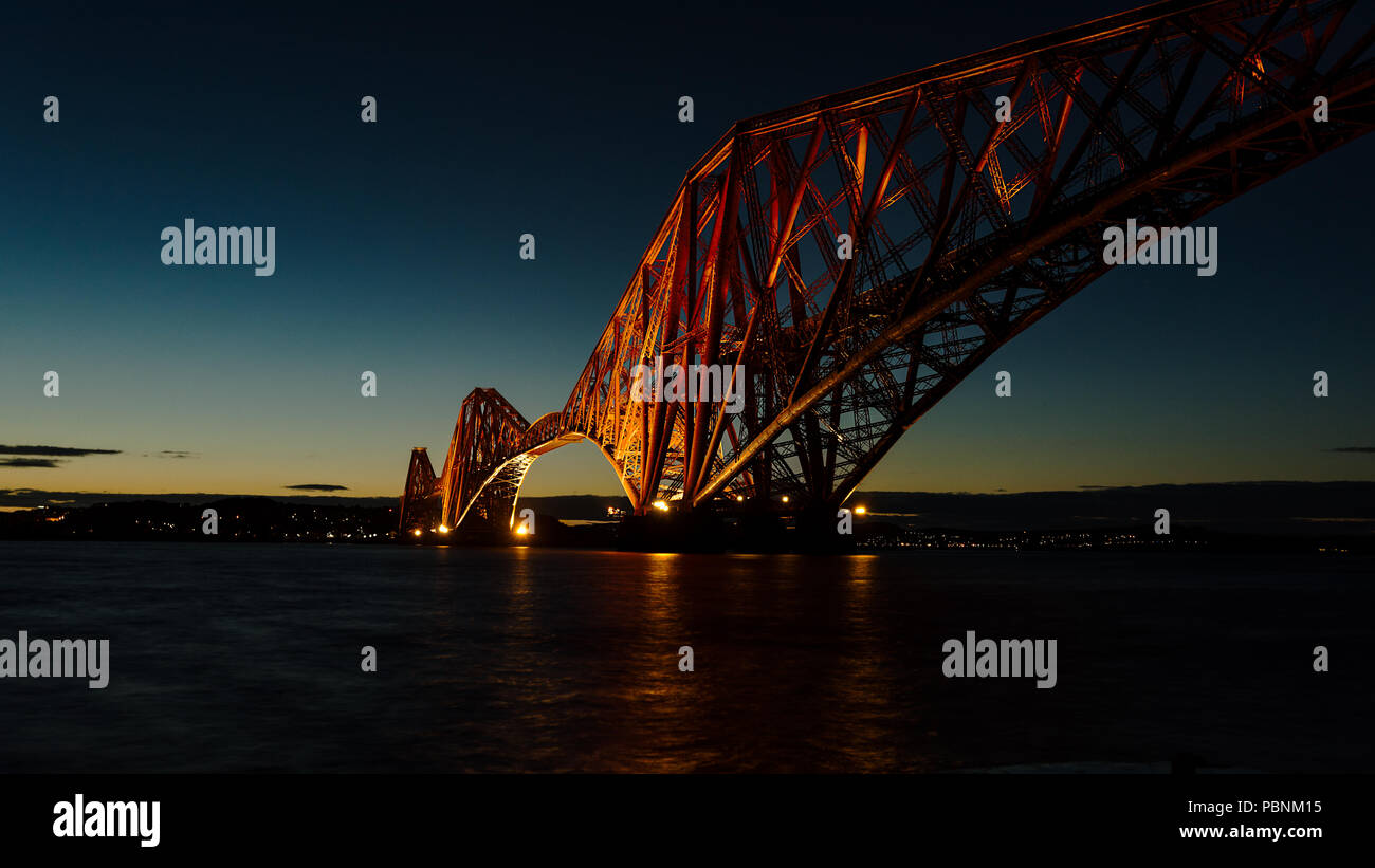 Il Forth Bridge crossing Firth of Forth illuminato alla fine del tramonto, Edimburgo, Scozia. Foto Stock