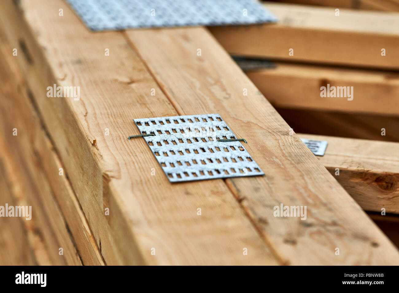 Una chiusura del connettore in metallo su piastre di copertura in legno a capriate con profondità di campo Foto Stock