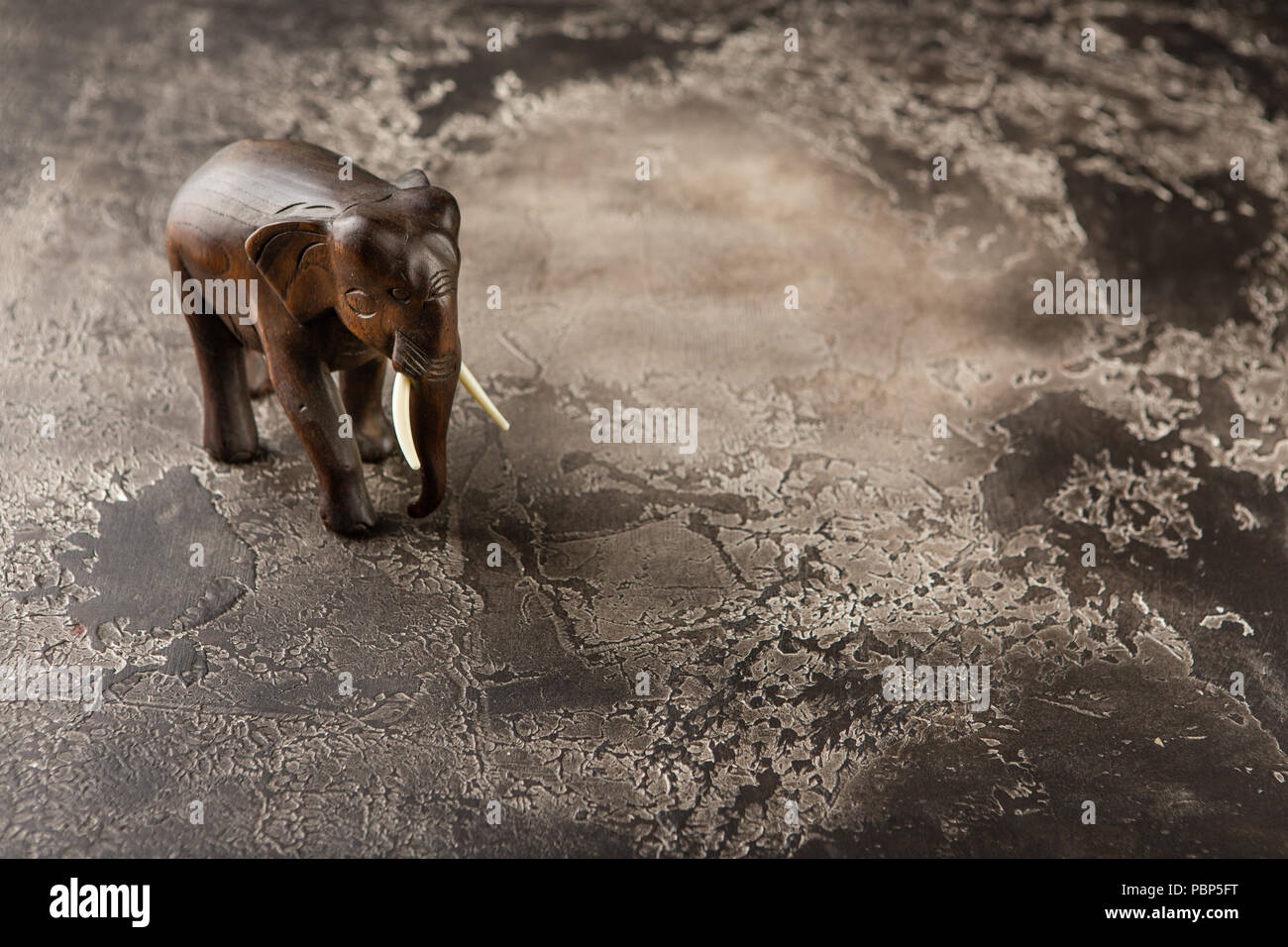 Figurina di un elefante in legno su un sfondo di calcestruzzo Foto Stock