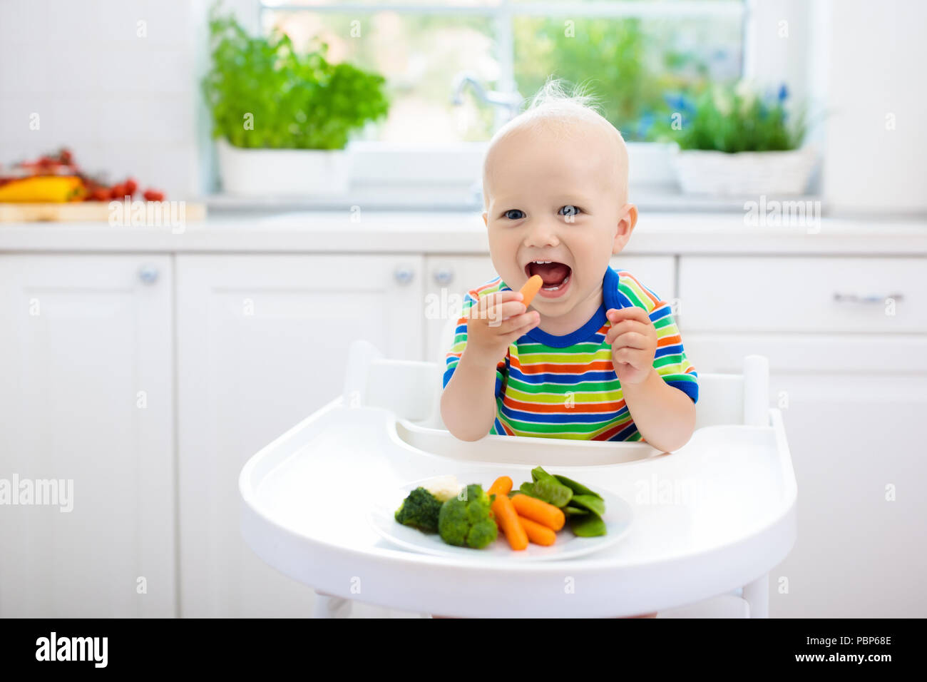 Carino baby mangiare le verdure in cucina bianca. Di svezzamento per neonati  e bambini piccoli. Little