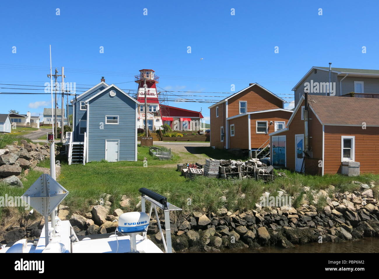 Una vista del weatherboard cottages e Red & White faro nella zona del porto di Cheticamp sul Cabot Trail, Cape Breton Island, Nova Scotia Foto Stock