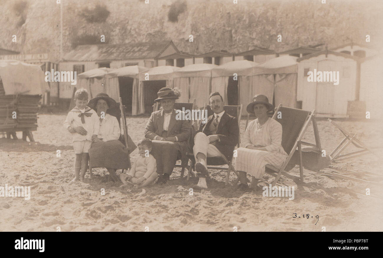 Vintage fotografia di un gruppo familiare rilassante nella loro sedie a sdraio su una spiaggia britannico Foto Stock