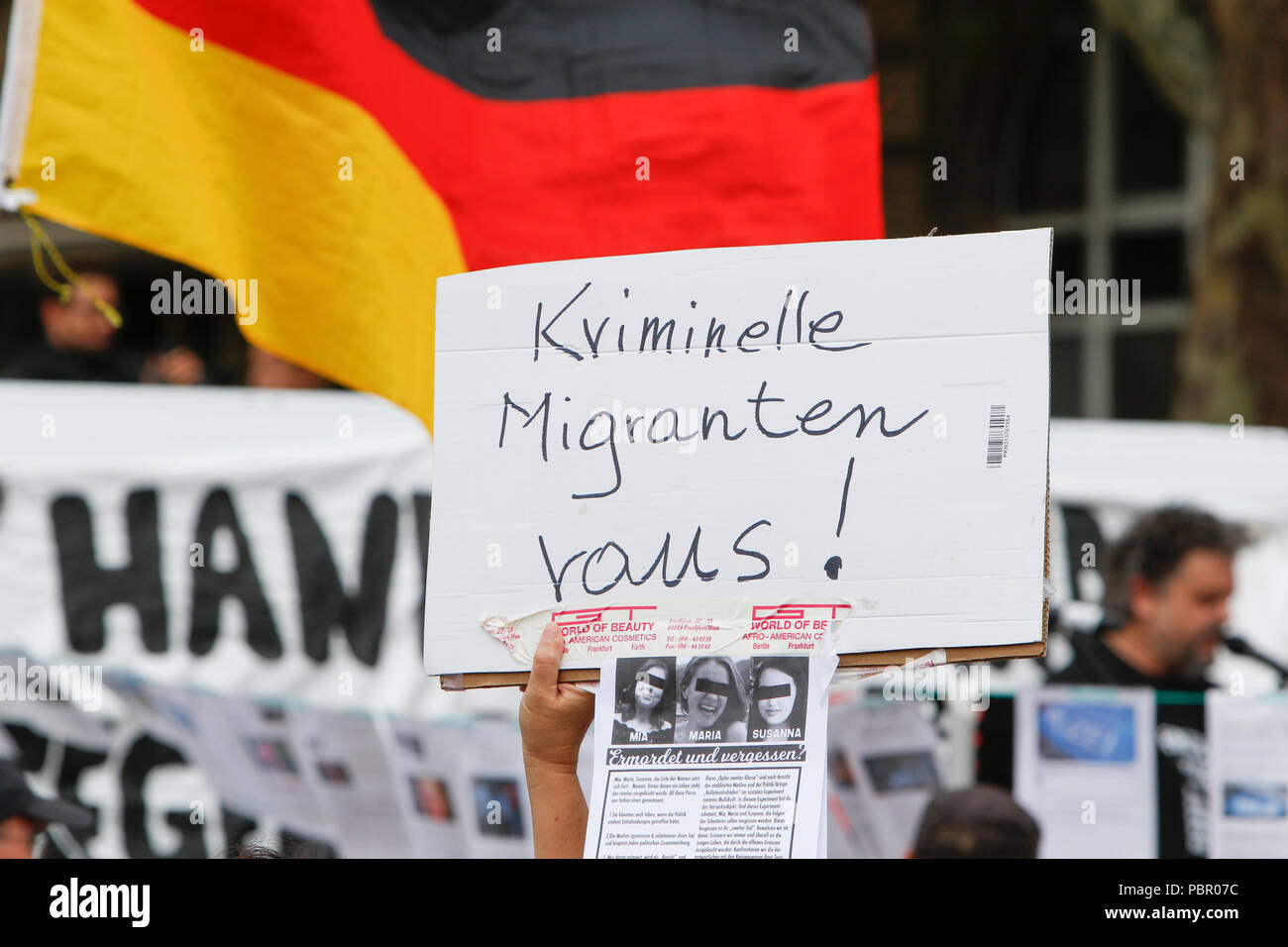 Wiesbaden, Germania. Il 29 luglio 2018. Un ala destra protester sorregge un cartello che recita "immigrati criminali fuori!'. A destra i manifestanti di mano in mano - Gegen die Gewalt auf unseren Strasen (mano nella mano - contro la violenza sulle nostre strade) movimento tenuto un governo anti-rally di Wiesbaden. La protesta si è svolta sotto il pretesto di una veglia per l'adolescente Susanna F, che sarebbe stato ucciso da un rifugiato a Wiesbaden. Il rally è stato affrontato da diversi anti-casse del governo, che ha chiesto al governo di dimettersi. Foto Stock