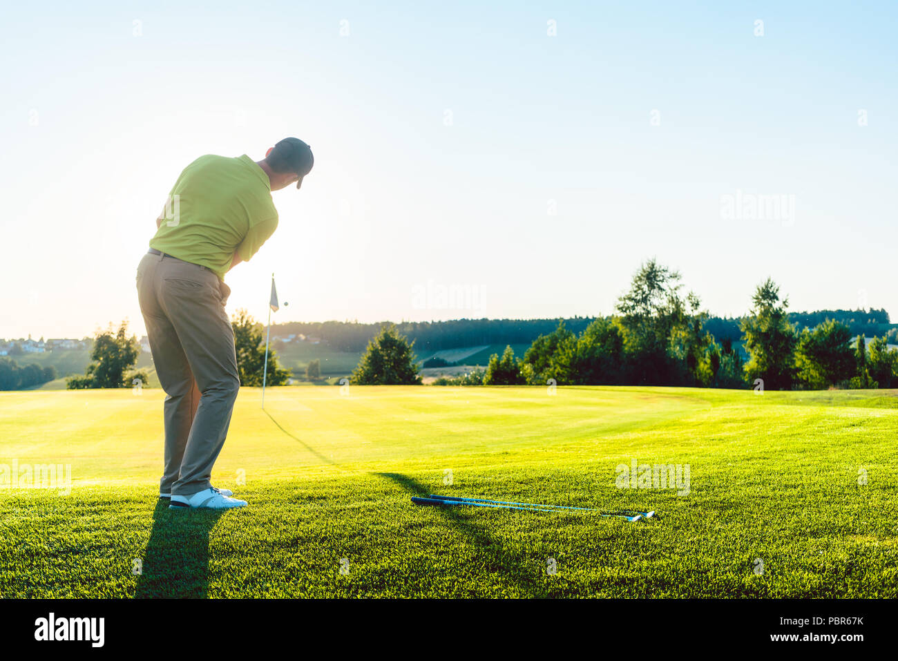 Esperto golfista maschio di colpire la pallina da golf verso la coppa Foto Stock