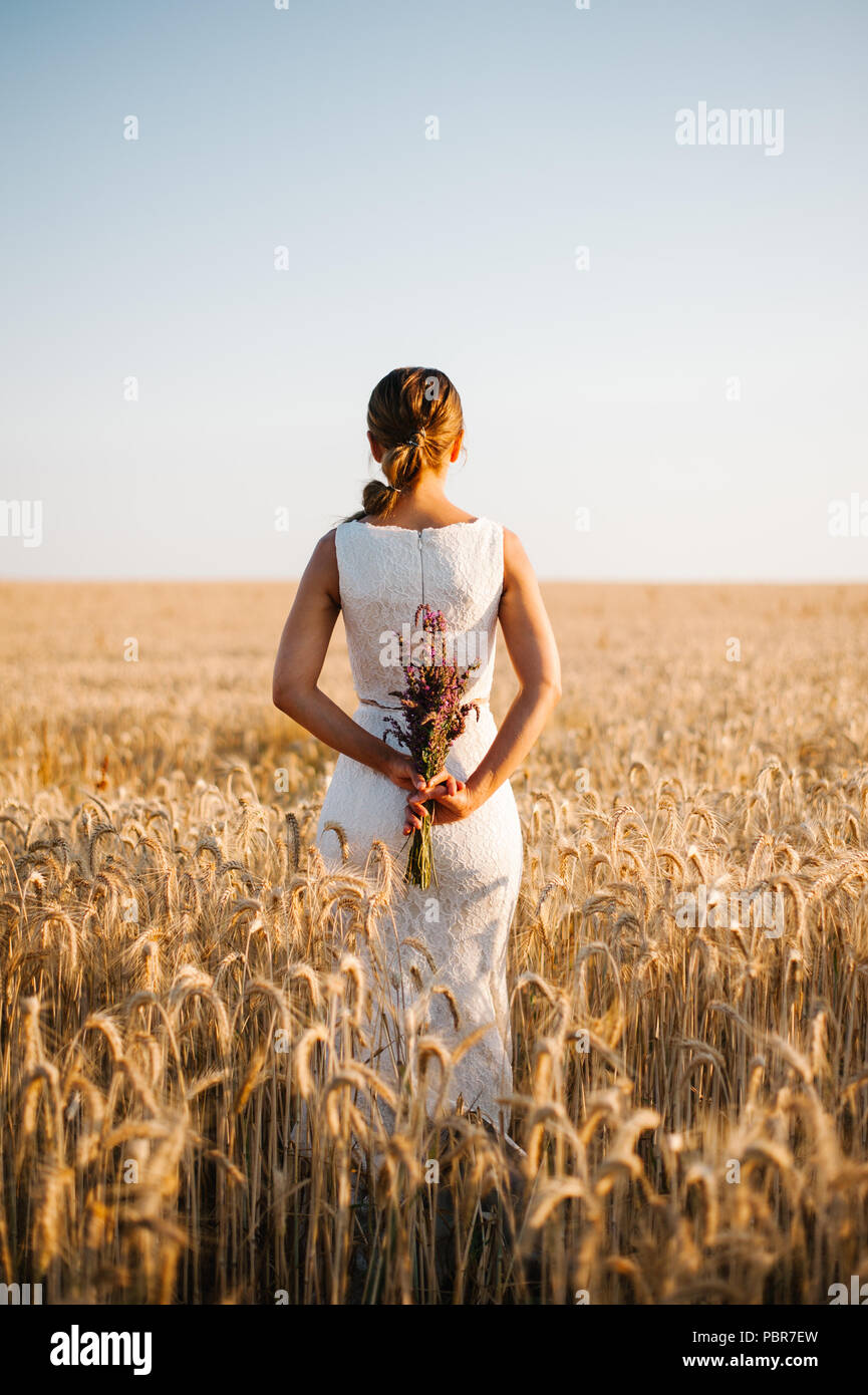 Sposa tiro con un mazzo di fiori in un campo Foto Stock