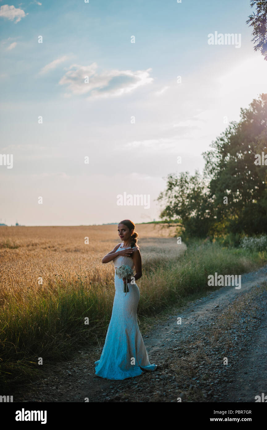 Sposa tiro con un mazzo di fiori in un campo Foto Stock