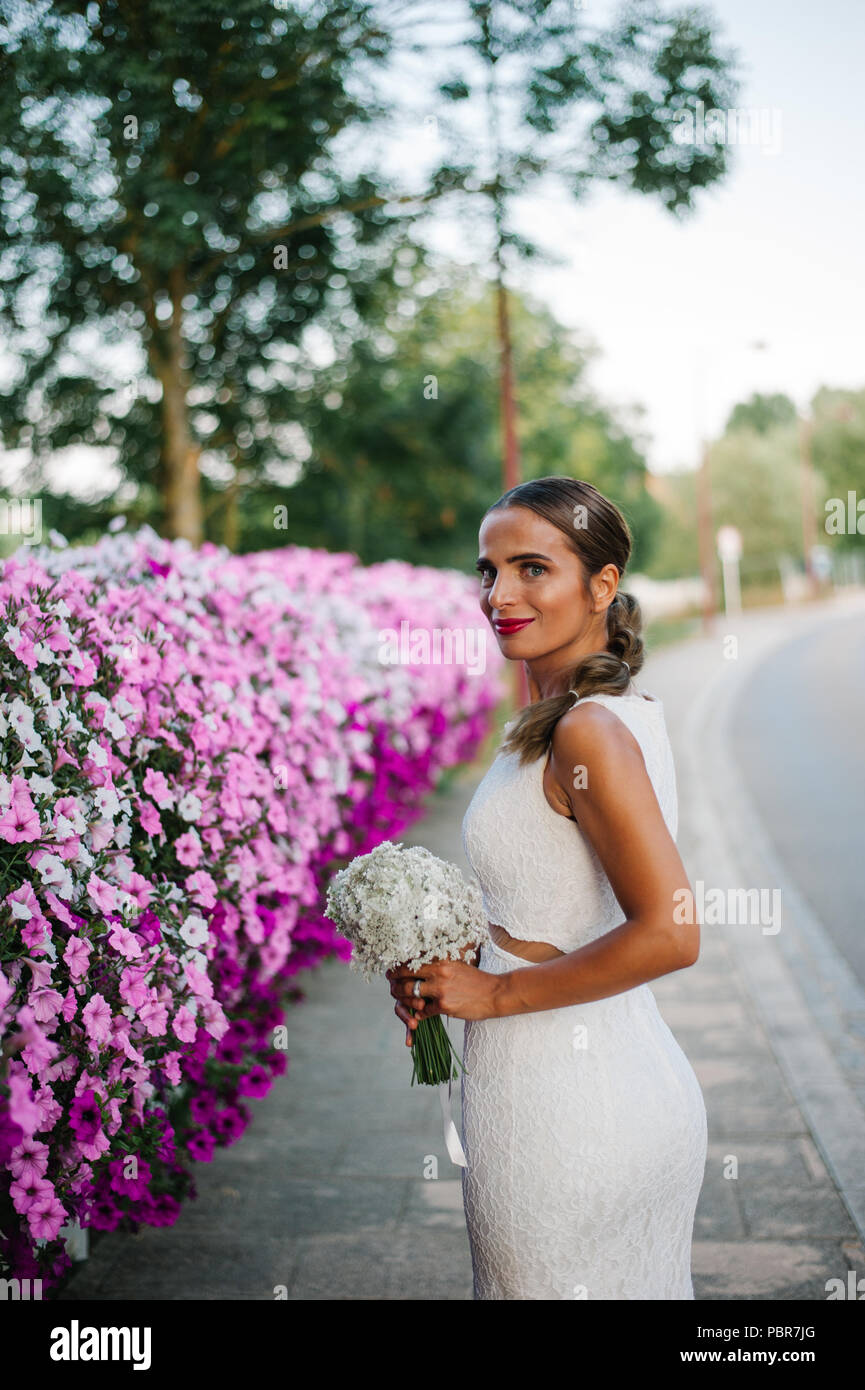 Sposa le riprese con i fiori vicino alla strada Foto Stock