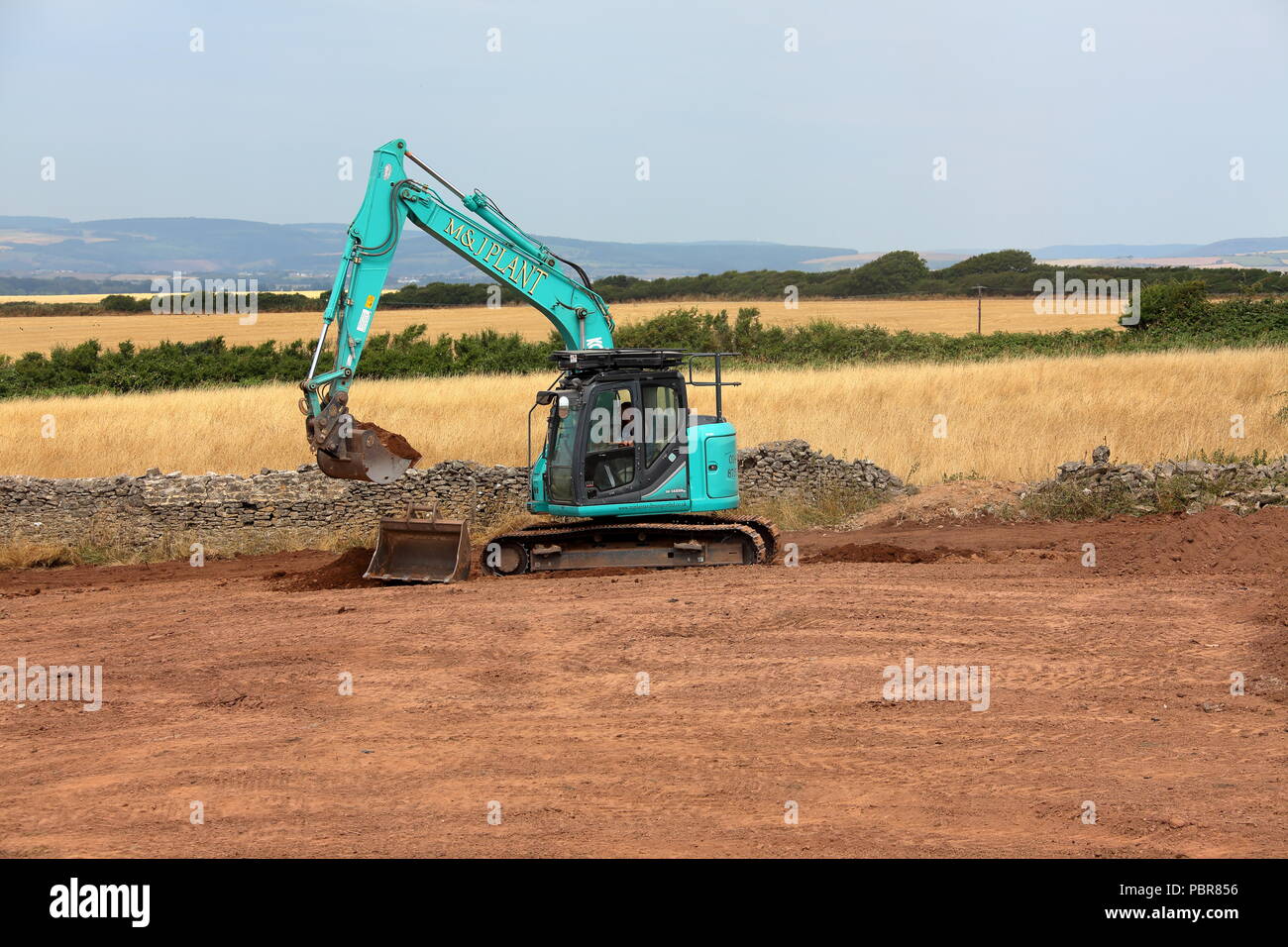 Un incaricato di recente grande escavatore cingolato livellare la terra in un restaurato recentemente campo prima di essere restituito all'agricoltore. Foto Stock