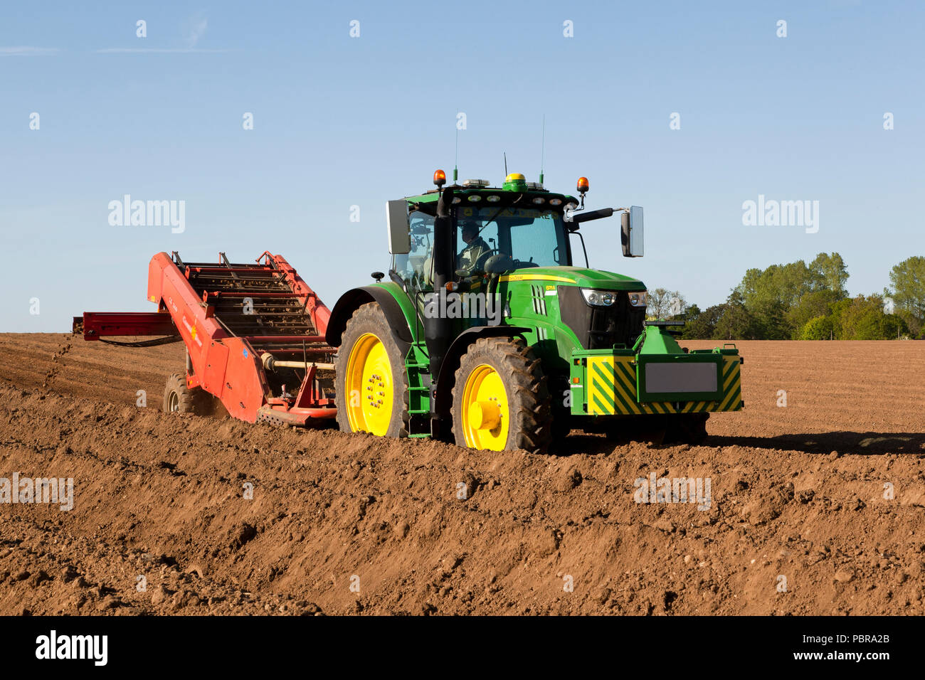 Un agricoltore alla guida di un trattore e di un separatore di pietra macchina  per piantare patate Foto stock - Alamy