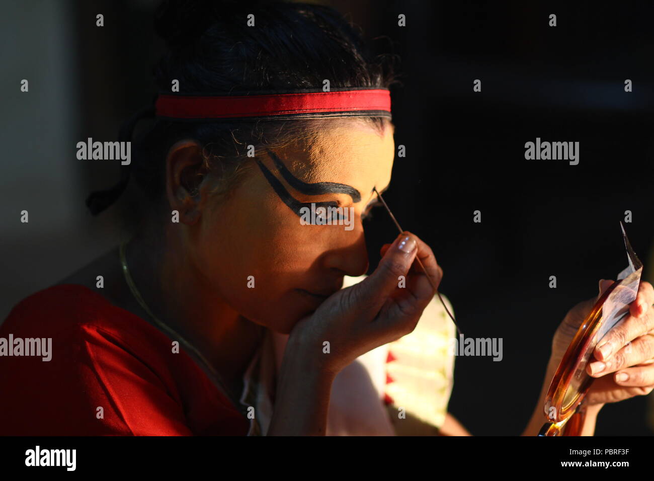 Un artista Koodiyattam ottenere pronto per le prestazioni mettendo la faccia della vernice. Artista messa faccia painint, artista Koodiyattam ottenere pronto ad eseguire. Foto Stock