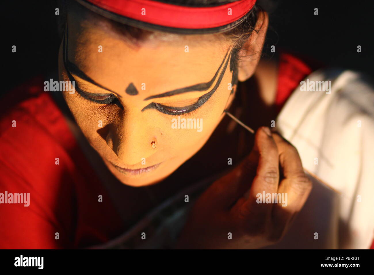 Un artista Koodiyattam ottenere pronto per le prestazioni mettendo la faccia della vernice. Artista messa faccia painint, artista Koodiyattam ottenere pronto ad eseguire. Foto Stock