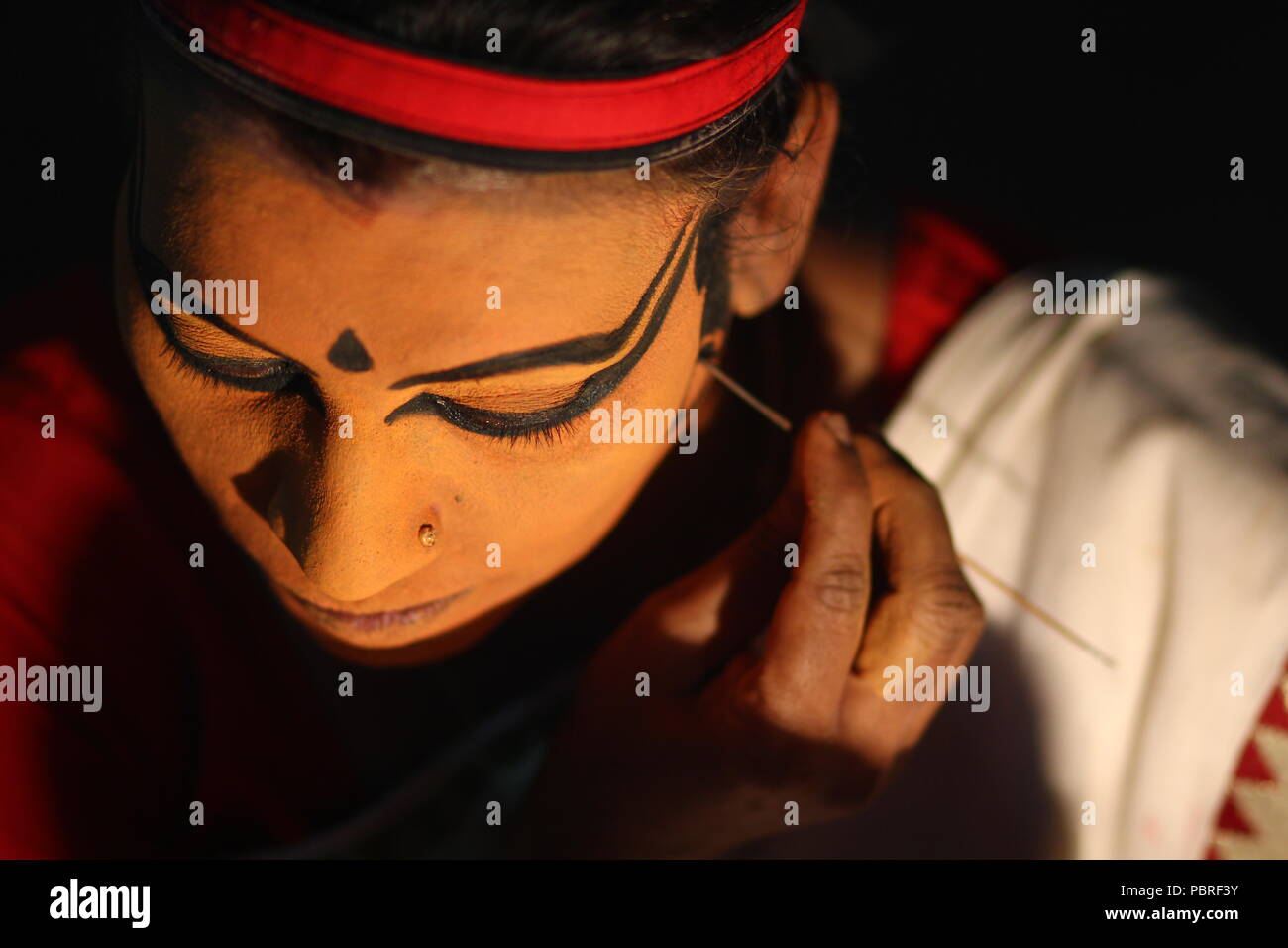 Un artista Koodiyattam ottenere pronto per le prestazioni mettendo la faccia della vernice. Artista messa faccia painint, artista Koodiyattam ottenere pronto ad eseguire. Foto Stock