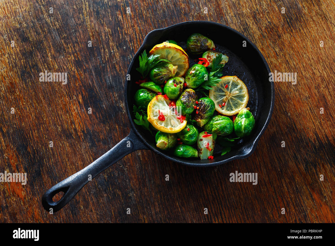 Broccoli fritti serviti in ghisa padella sul tavolo di legno vista superiore sano cibo vegetariano Foto Stock