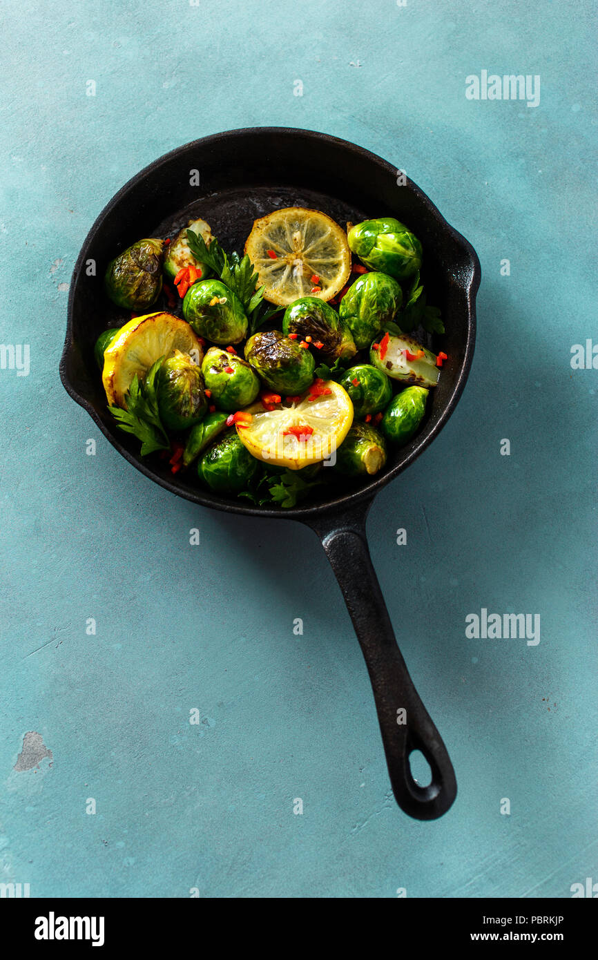 Una sana alimentazione vegetariana. Ghisa padella con broccoli fritti sulla pietra blu sfondo, vista dall'alto Foto Stock