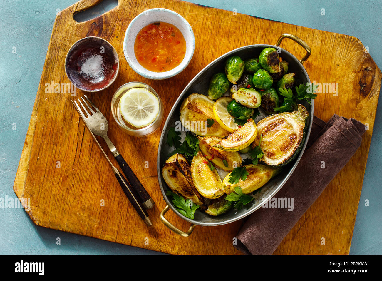 Broccoli fritti con zucchine servita in ghisa padella su pietra blu sfondo, vista dall'alto una sana cucina vegetariana Foto Stock