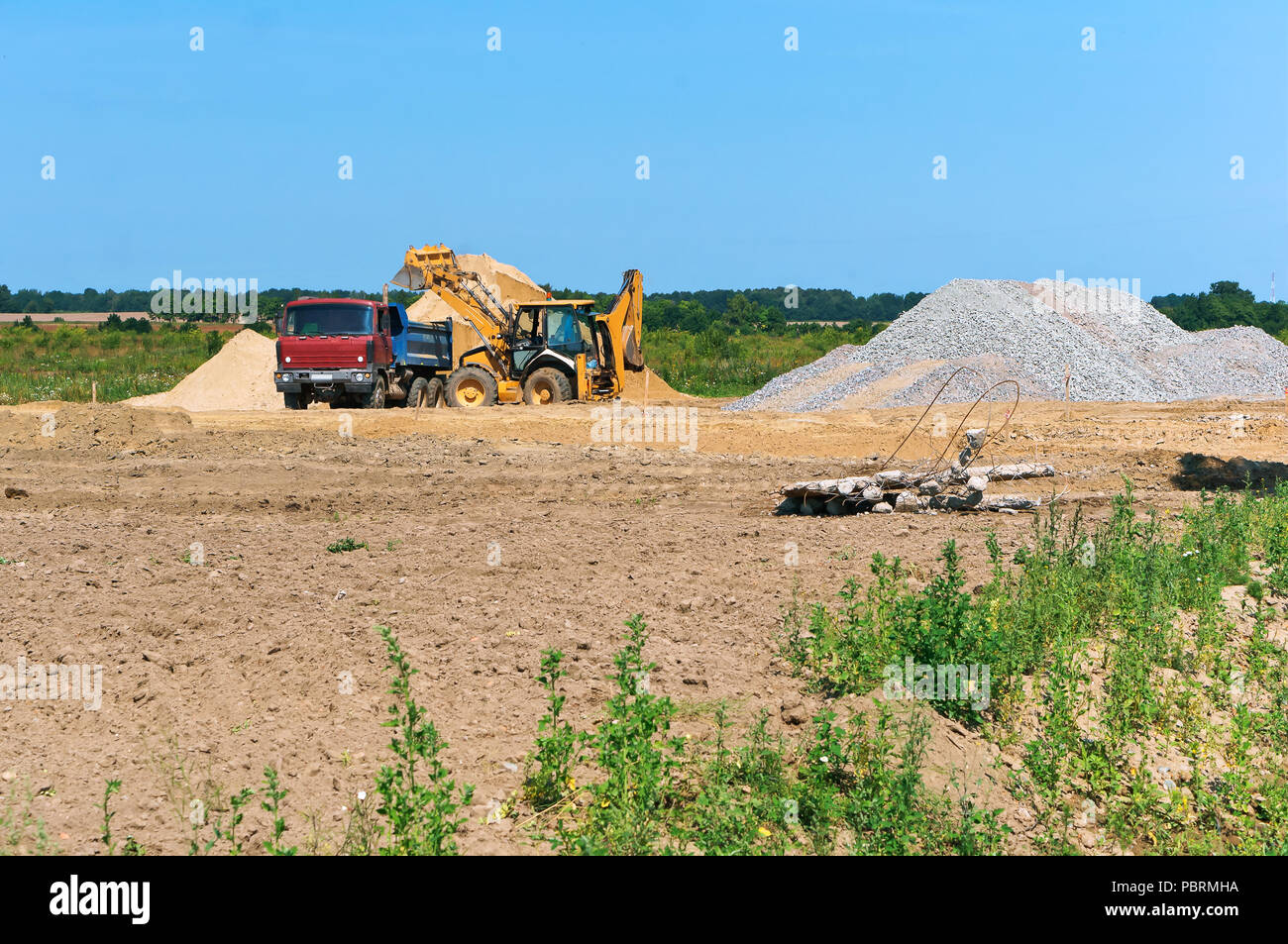 Carrello escavatore e accanto a una pila di sabbia, cava mineraria di sabbia Foto Stock