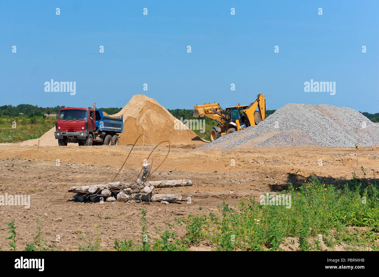 Carrello escavatore e accanto a una pila di sabbia, cava mineraria di sabbia Foto Stock