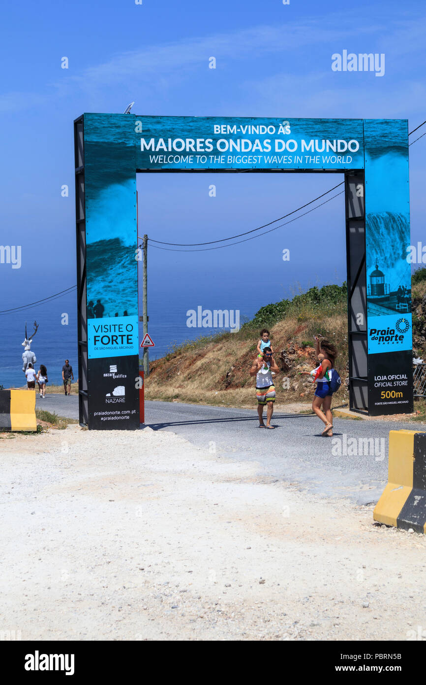 I turisti sotto il grande "Benvenuti alla più grande delle forme d'onda in tutto il mondo " portale di ingresso a Nazare Portogallo Foto Stock