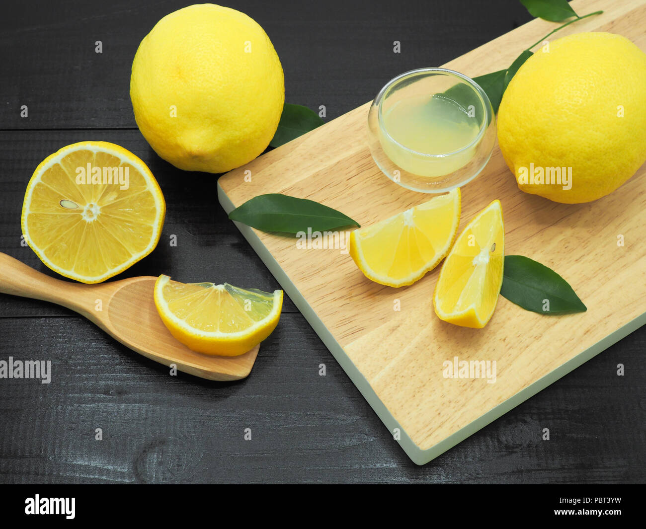 Succo di limone fresco in una piccola ciotola e fetta di limone su legno scuro dello sfondo Foto Stock