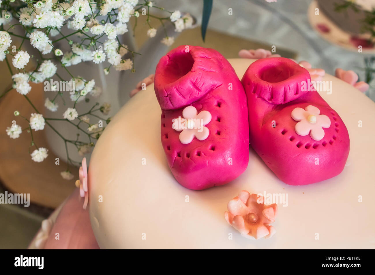 Baby shower torta con un po' di marzapane rosa scarpine per una ragazza e un allestimento floreale Foto Stock