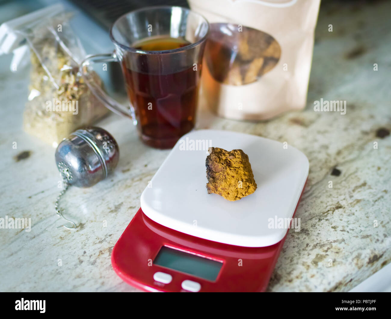 Sul bancone della cucina, sulla bilancia elettronica, abbiamo pesare un pezzo di fungo chaga. Dietro la scala possiamo vedere una coppa trasparente di chaga bevanda. Foto Stock