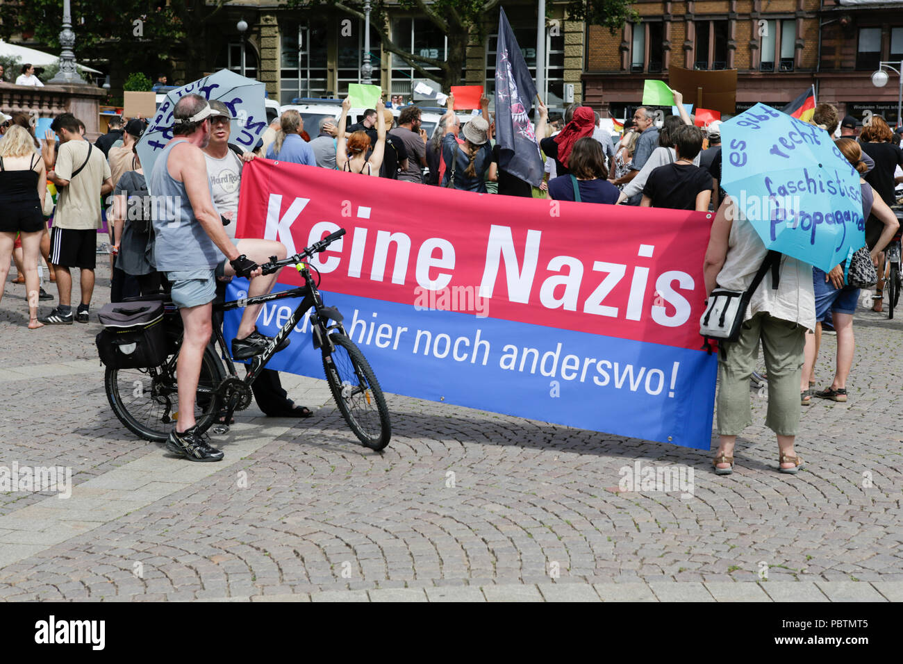 Wiesbaden, Germania. 29 Luglio, 2018. Contatore protester tenere un banner che recita "No Nazis - né qui né altrove". A destra i manifestanti di mano in mano - Gegen die Gewalt auf unseren Strasen (mano nella mano - contro la violenza sulle nostre strade) movimento tenuto un governo anti-rally di Wiesbaden. La protesta si è svolta sotto il pretesto di una veglia per l'adolescente Susanna F, che sarebbe stato ucciso da un rifugiato a Wiesbaden. Il rally è stato affrontato da diversi anti-casse del governo, che ha chiesto al governo di dimettersi. Credito: Michael Debets/Pacific Press/Alamy Live News Foto Stock