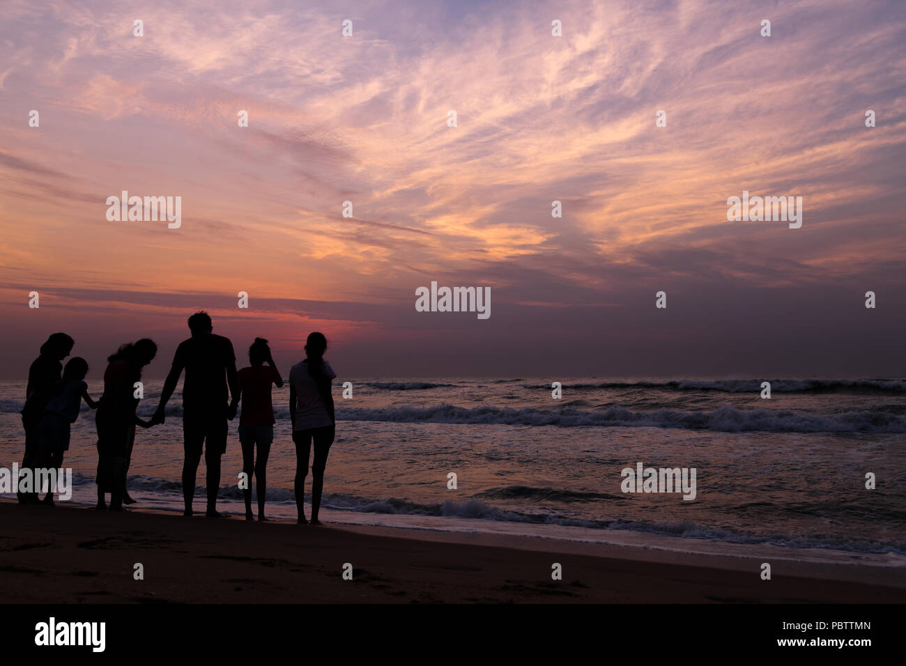 Una famiglia in attesa per il sorgere del sole sulla spiaggia di Marina, Chennai. La bellezza delle cose semplici della vita, aspettando il sorgere del sole con i vostri cari Foto Stock