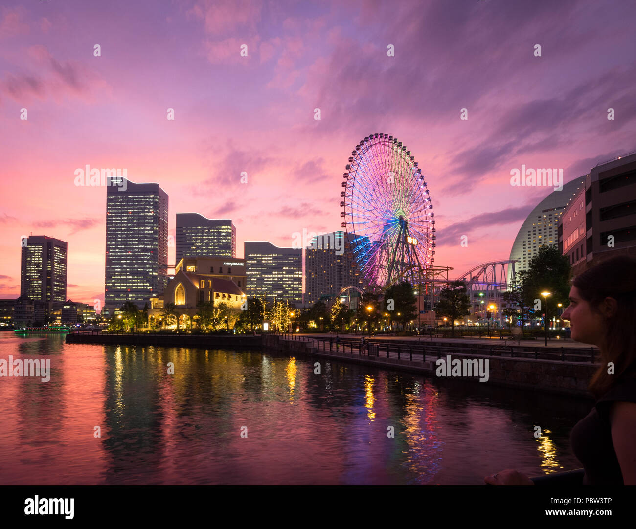 Una vista di una brillante tramonto sulla skyline di Yokohama a Minato-Mirai e il Cosmo orologio 21 ruota panoramica Ferris, come si vede da Unga Park. Yokohama, Giappone. Foto Stock