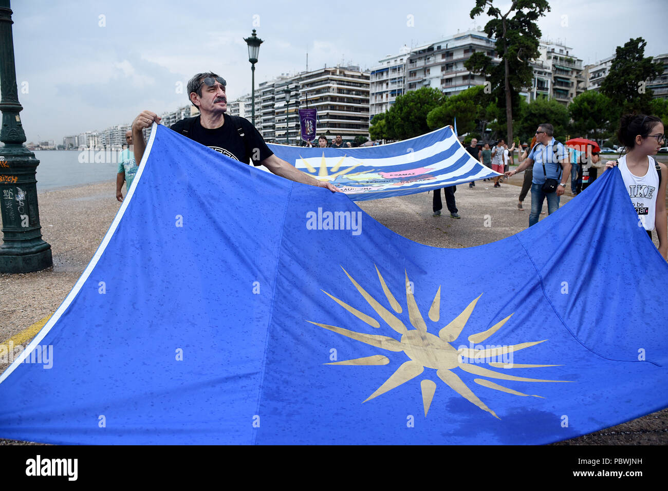 Salonicco, Grecia. Il 30 luglio, 2018. Le persone in possesso di una bandiera con la Vergina Sun come essi marzo presso il lungomare di Salonicco. Centinaia di persone hanno ballato al mare del nord del greco di Salonicco, una tradizionale danza macedone chiamato ''Macedonian Syrto'', per protestare contro il Prespa accordo per quanto riguarda la Macedonia Naming controversia tra la Grecia e la Macedonia. Credito: Giannis Papanikos/ZUMA filo/Alamy Live News Foto Stock