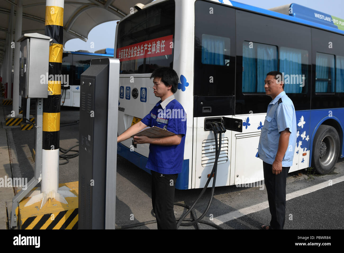 Hangzhou, cinese della Provincia di Zhejiang. Il 30 luglio, 2018. Un bus elettrico viene addebitato al Gongkang manutenzione stradale dalla stazione di Hangzhou, a est della capitale cinese della Provincia di Zhejiang, 30 luglio 2018. Hangzhou Trasporto Pubblico gruppo, fin dal 2008, ha introdotto diversificata di energia pulita gli autobus per realizzare il risparmio energetico e la riduzione di emissioni nel settore dei trasporti pubblici. Fino ad ora, 2,274 bus elettrici sono state messe in funzione su oltre un centinaio di rotte. Credito: Huang Zongzhi/Xinhua/Alamy Live News Foto Stock