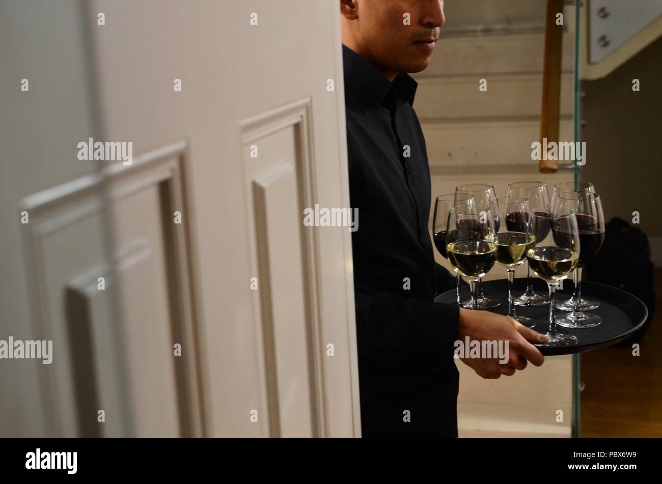 Cameriere che offre bevande rinfrescanti per persone a caso per interni Foto Stock