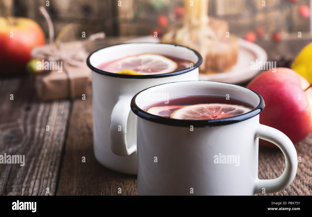 Frutta calda tè con le fette di limone in bianco rustico mug sul tavolo di legno, intime calda bevanda invernale Foto Stock