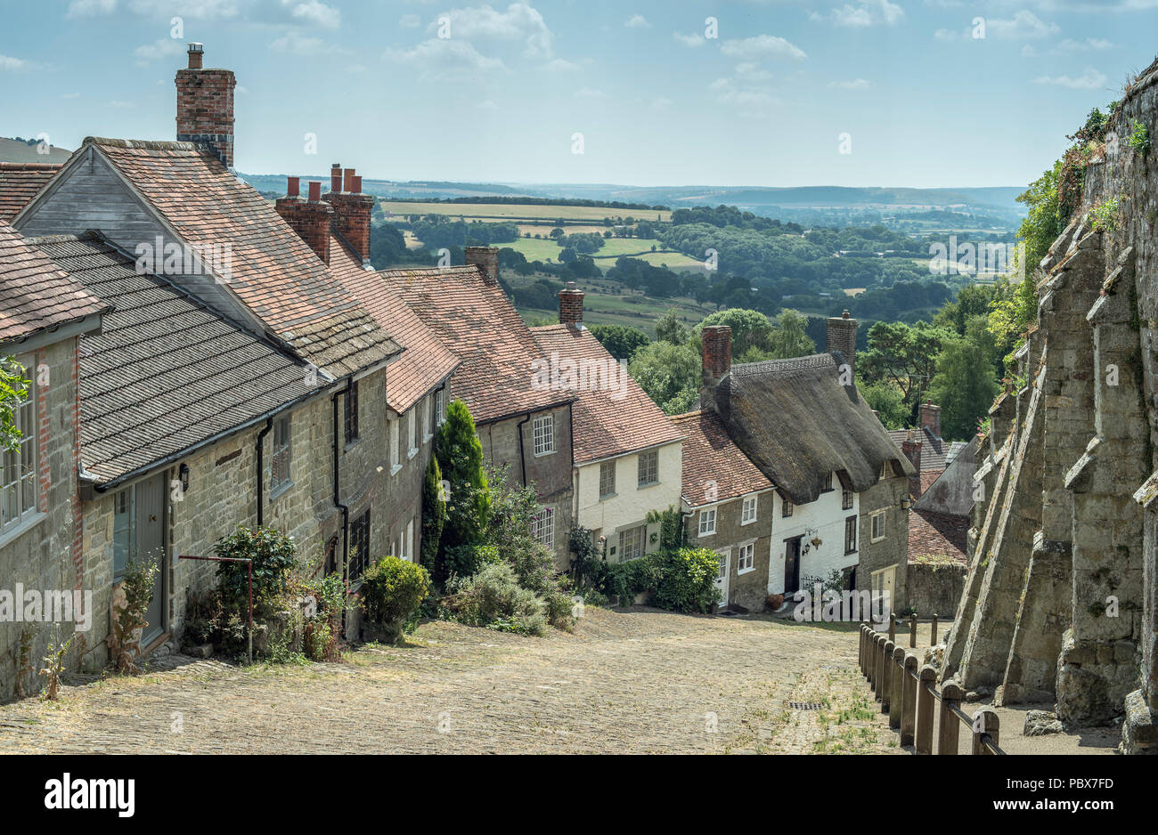 Tradizionale inglese britannico città vista orizzontale con cottage con il tetto di paglia, vecchie case e terreni agricoli Foto Stock