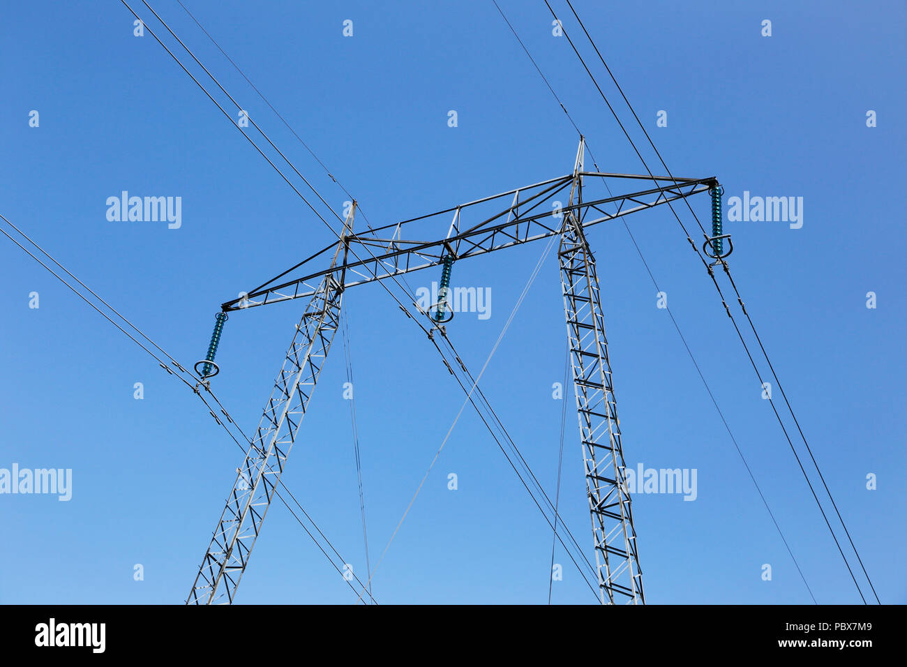 Linea elettrica ad alta tensione con una torre isolata contro un cielo blu. Foto Stock