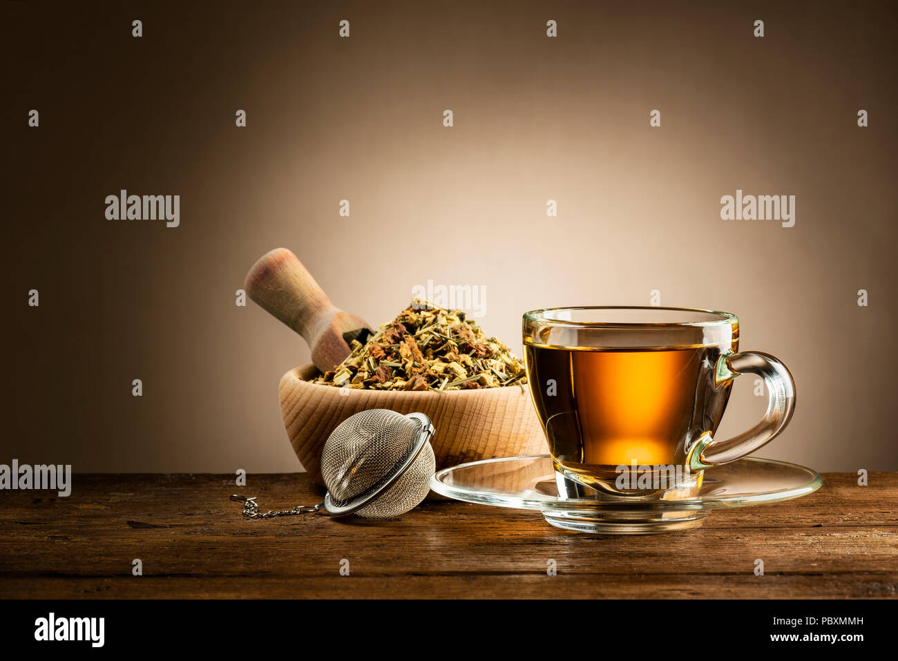 Bicchiere di vetro di tè con infusore e tè alle erbe su un tavolo