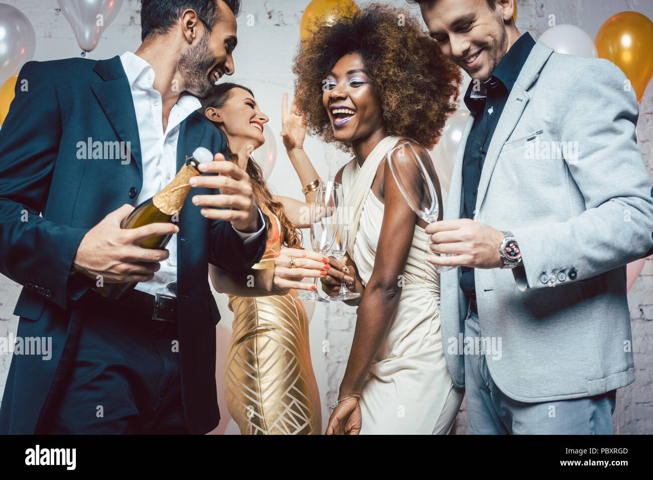 Uomo di apertura della bottiglia di champagne sulla celebrazione nel club Foto Stock