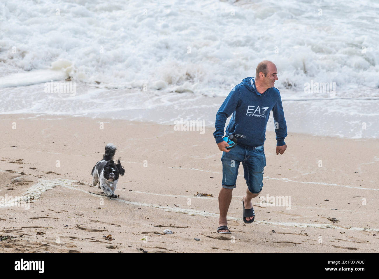 Un uomo giocando con il suo cane su una spiaggia. Foto Stock