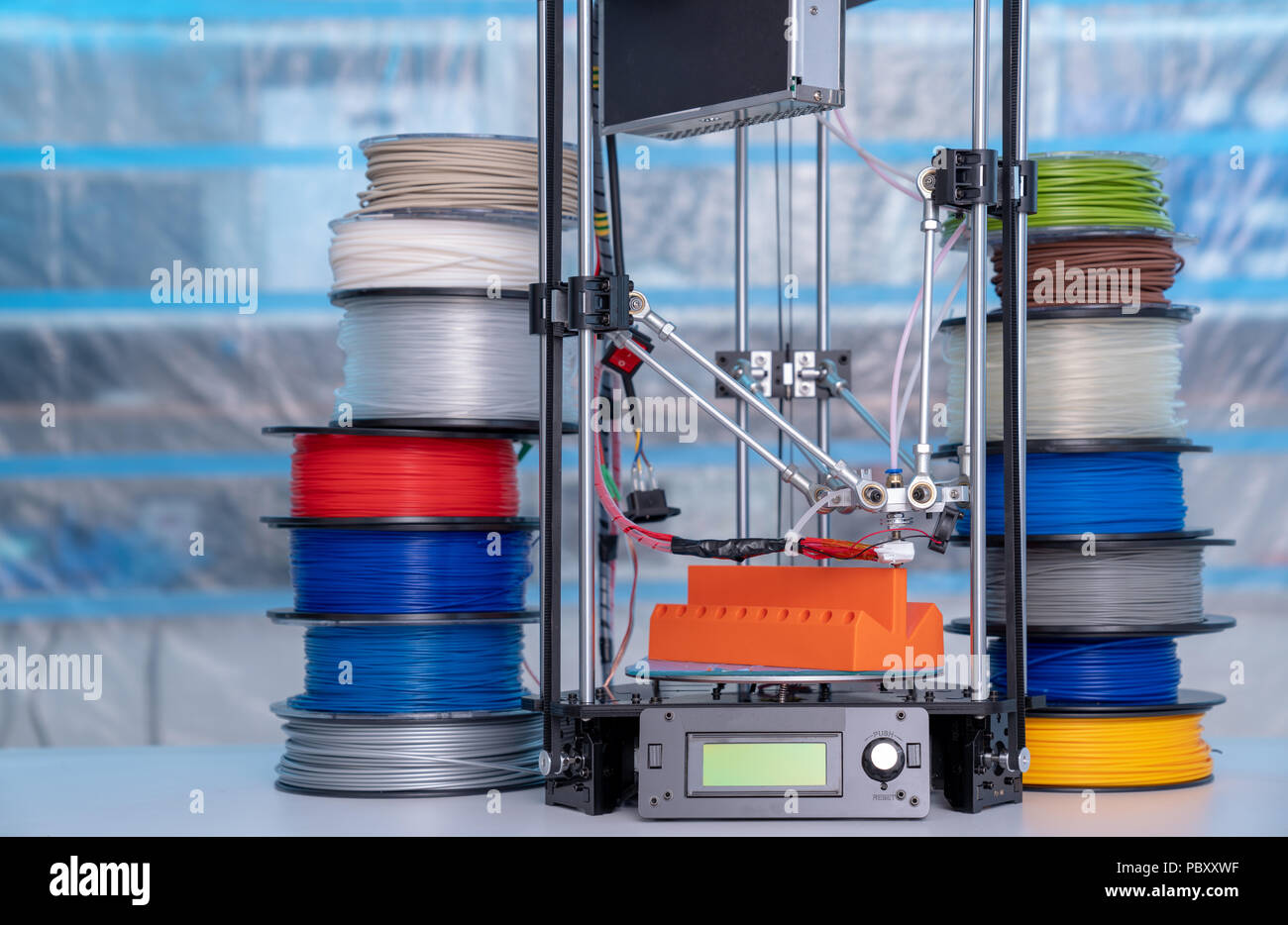 ABS e PLA filament accanto alla stampante 3D. Bobine di plastica Foto Stock
