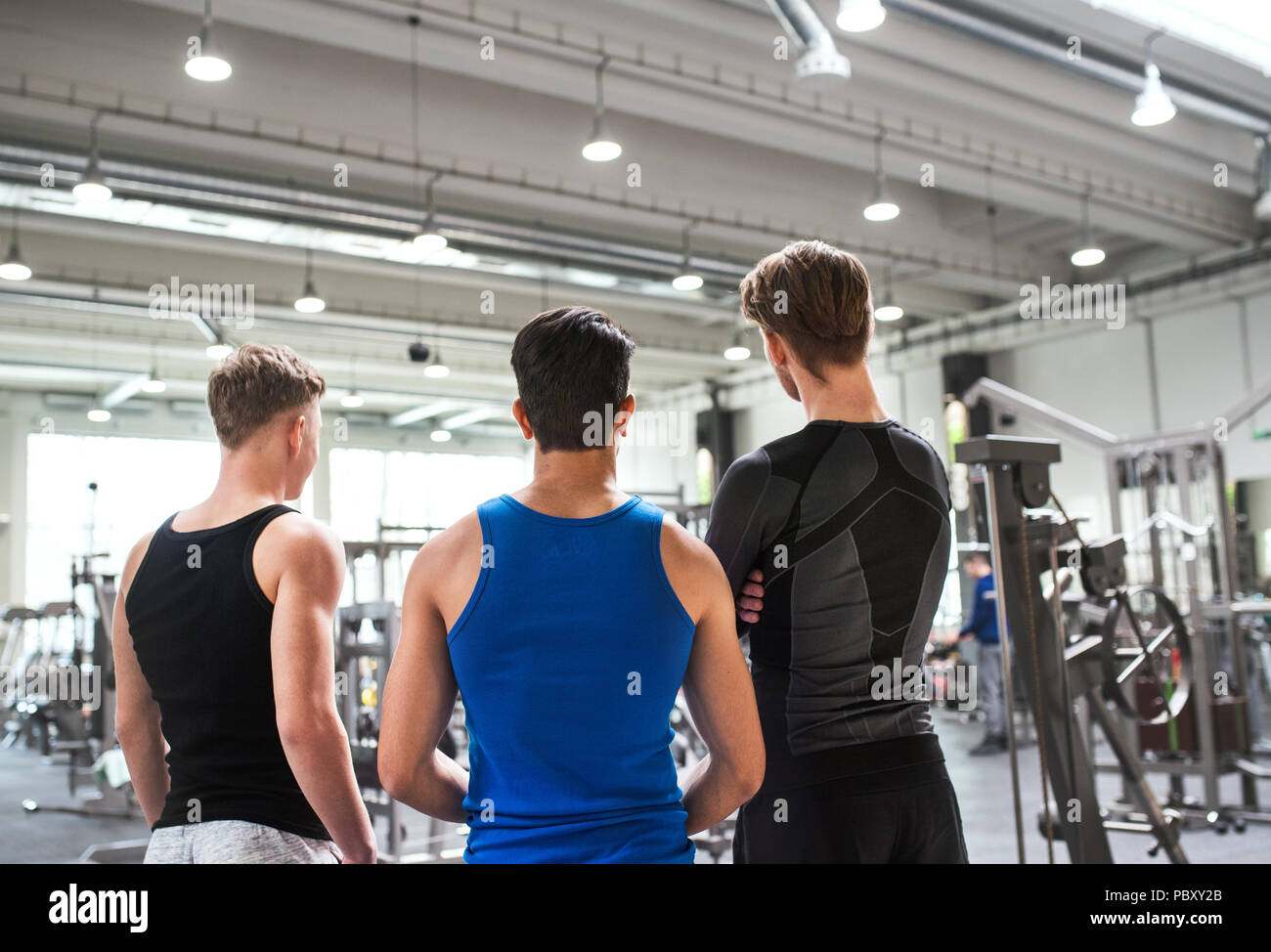 Giovani amici nella moderna palestra crossfit, permanente e la conversazione. Vista posteriore. Foto Stock