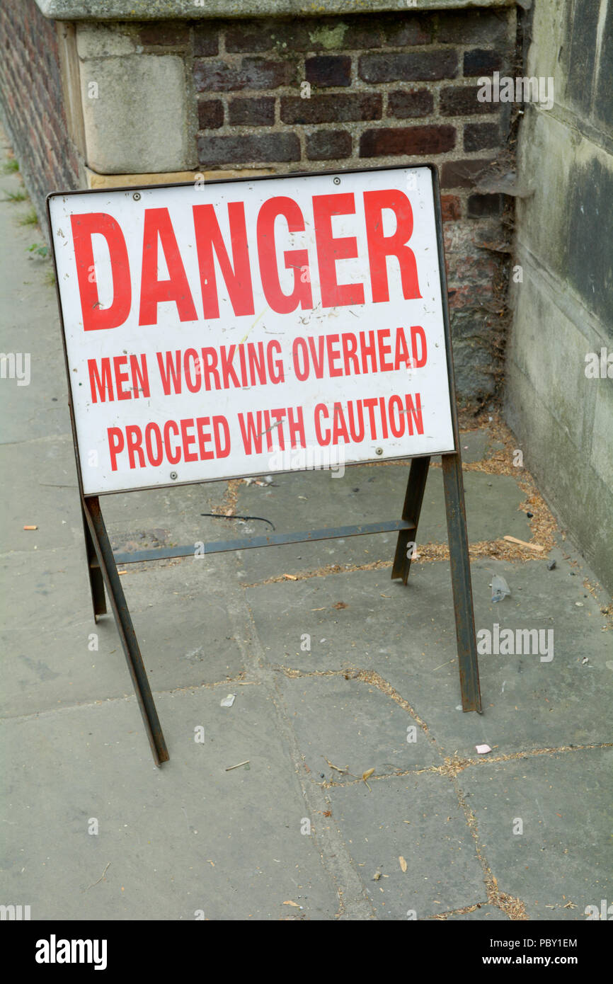 Pericolo - gli uomini al lavoro in alto - Procedere con cautela sul lato marciapiede Foto Stock